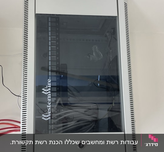 ארון תקשורת מותקן על קיר עם כבלי רשת ופאנל חיבורים